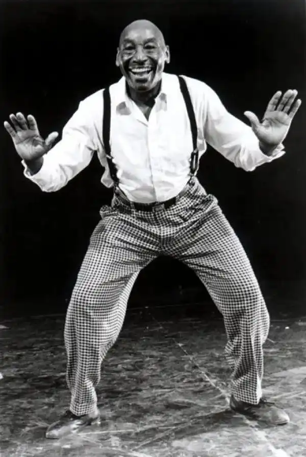 Frankie Manning in later years, smiling with his hands raised mid-dance