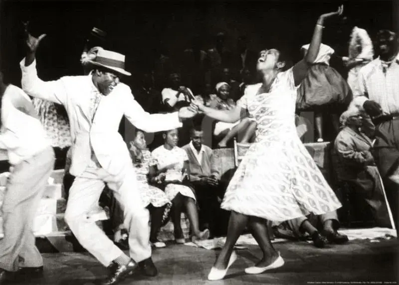A couple dancing Lindy Hop in front of a seated crowd
